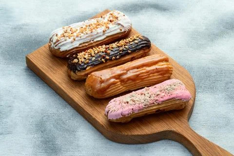 Assorted eclairs on a pastel top view Traditional French dessert Stock Photos
