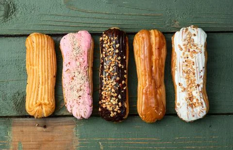 Assorted eclairs on a pastel top view Traditional French dessert Stock Photos