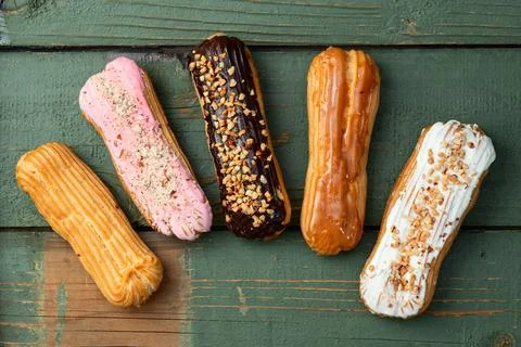 Assorted eclairs on a pastel top view Traditional French dessert Stock Photos