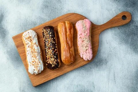 Assorted eclairs on a pastel top view Traditional French dessert Stock Photos