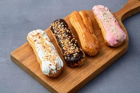 Assorted eclairs on a pastel top view Traditional French dessert Stock Photos
