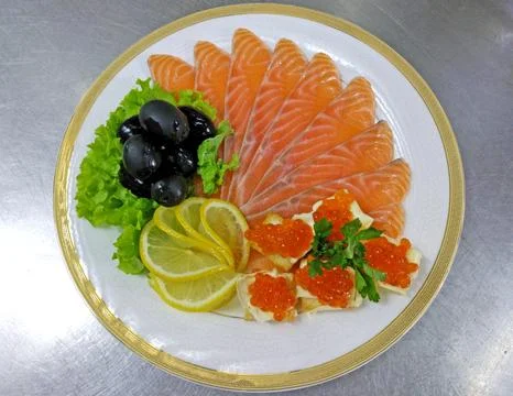 Assorted fish: salmon, red caviar, olives and lemon on a large plate Stock Photos