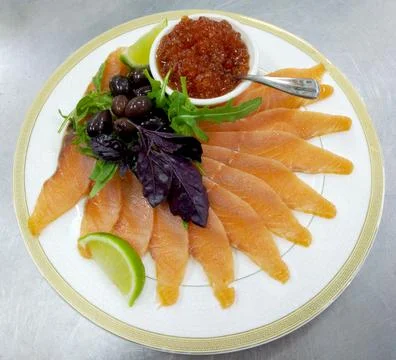 Assorted fish: salmon, red caviar, olives and lemon on a large plate Stock Photos