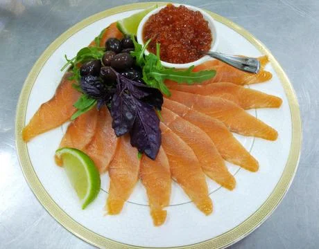 Assorted fish: salmon, red caviar, olives and lemon on a large plate Stock Photos