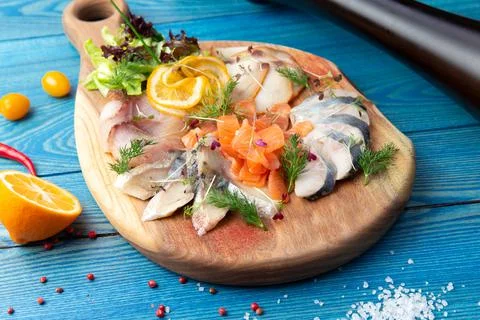 Assorted fish slices on a board. On a blue, wooden background. Stock Photos