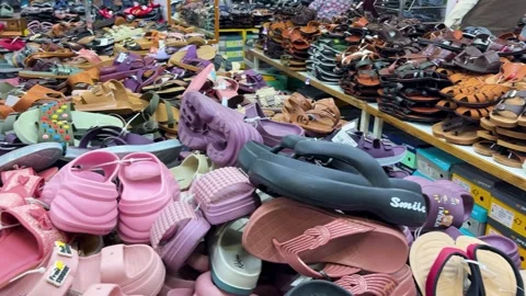 Assorted flip flops and casual sandals stacked on retail shop counter Stock Footage 332965205