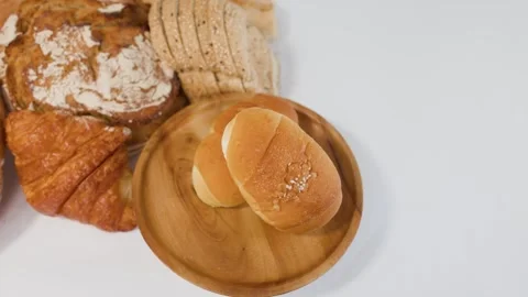 Assorted Fresh Bakery Bread and Rolls on Wooden Plate Stock Footage 337876775