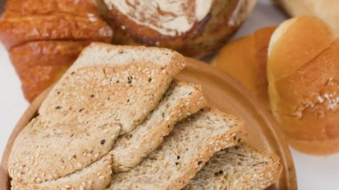 Assorted Fresh Bakery Bread and Sliced Whole Grain Toast on Wooden Plate Stock Footage 337876908