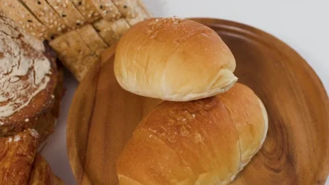 Assorted Fresh Bakery Bread and Dinner Rolls on Wooden Plate Stock Footage 338053896