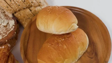 Assorted Fresh Bakery Bread and Rolls on Wooden Plate Stock Footage 338319205