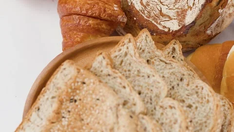 Assorted Fresh Bakery Breads and Sliced Whole Grain Toast on Wooden Plate Stock Footage 339513418