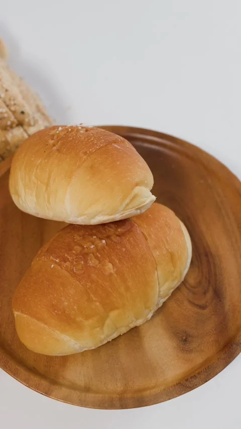Assorted Fresh Bread Rolls Rotating on a Wooden Plate Stock Footage 338421052