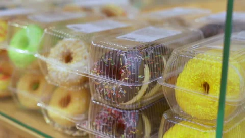 Assorted fresh donuts on display racks at the donut shop. Sweet doughnuts with Stock Footage 262410837