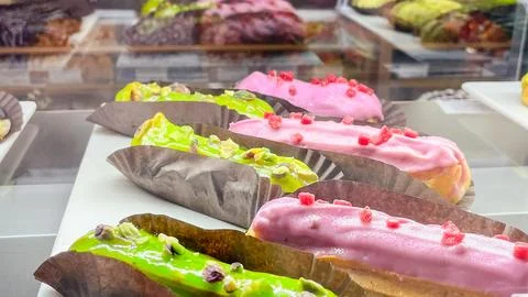 Assorted fresh eclairs with bright pink raspberry glaze and green pistachio.. Stock Photos