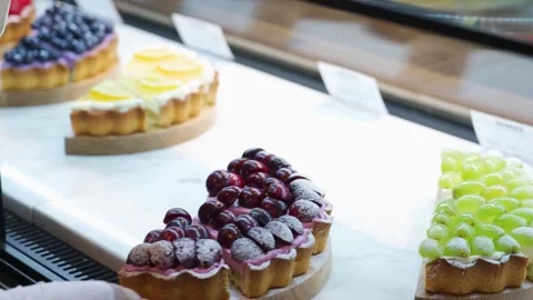 Assorted Fresh Fruit Tarts and Gourmet Pastries in Bakery Display Case Stock Footage 337751192