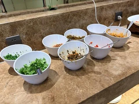 Assorted Fresh Salad Toppings in White Bowls on Marble Countertop Foto stock