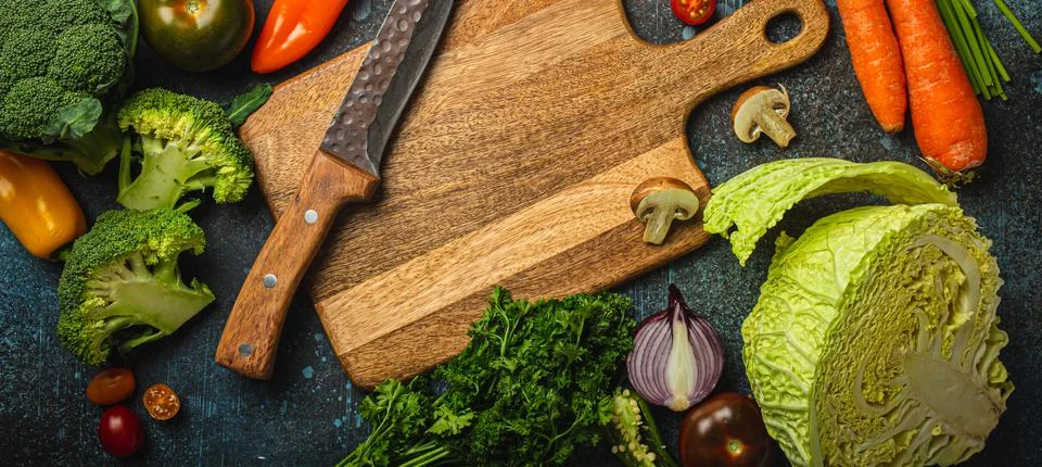 Assorted fresh vegetables on rustic concrete table with wooden cutting board in Stock Photos