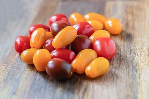 Assorted fresh yellow, red and black cherry tomatoes on a wooden background Stock Photos