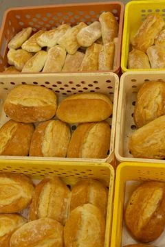 Assorted freshly baked bread rolls stacked in perforated baskets at market stall Stockfoto's