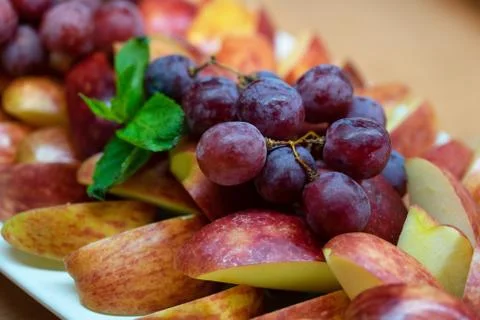 Assorted fruit - apples, grapes. Sliced fruit on a plate Stock Photos