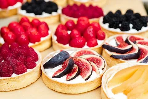 Assorted fruit tarts with berries figs and lemon slices Stock Photos