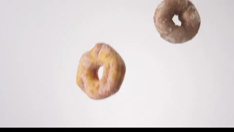 Assorted glazed and chocolate cake donuts raining on white slow motion macro Stock Footage 337909736