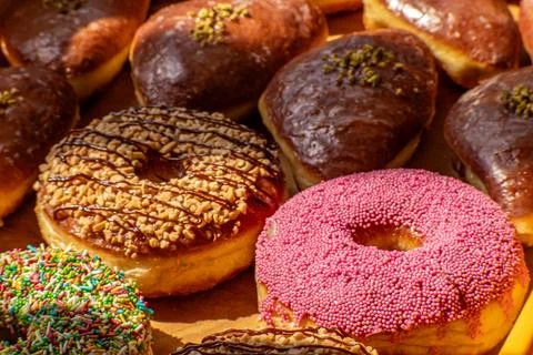 Assorted glazed and decorated donuts on a wooden tray in a bakery Stock Photos