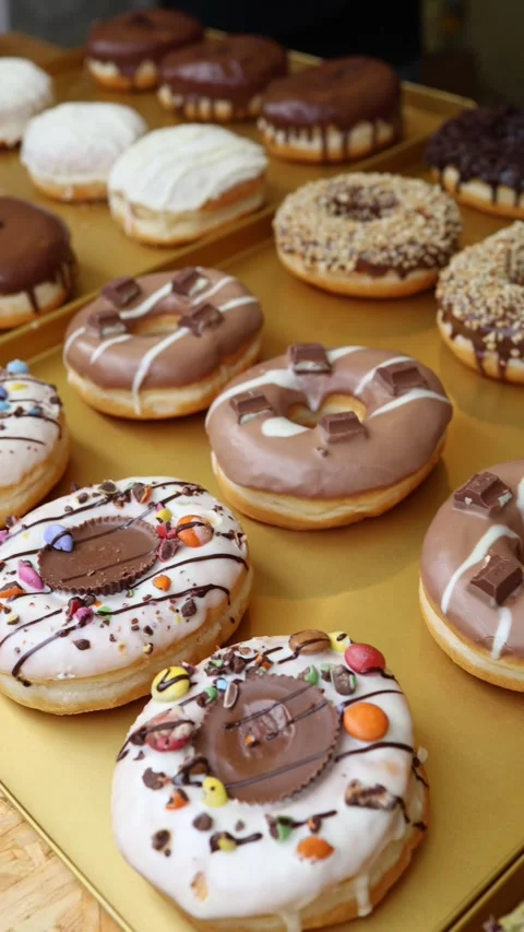 Assorted glazed donuts with chocolate candy toppings and colorful decorations di Video stock 346973791