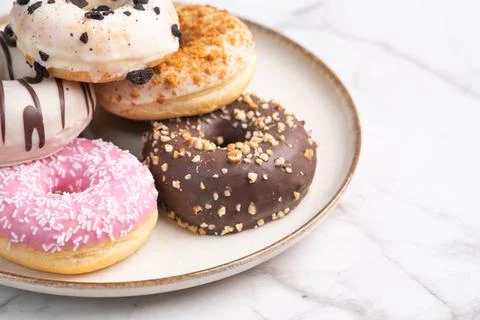 Assorted glazed donuts with toppings on marble table background Fotos Stock