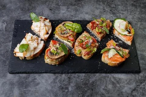 Assorted Gourmet Canaps On Black Slate Board for Elegant Party Platter and Stock Photos