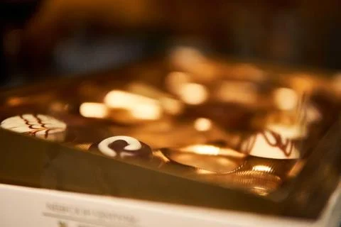Assorted gourmet chocolates arranged elegantly in a golden box at a celebratory Stock Photos