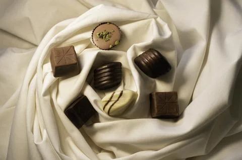 Assorted gourmet chocolates on elegant white fabric Stock Photos