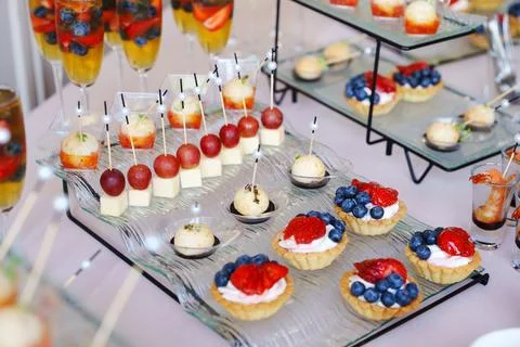 Assorted gourmet snacks and fruit tarts on a glass tray 스톡 사진