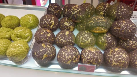 Assorted green matcha and dark chocolate cookie puffs displayed in bakery case 動画素材 317886038