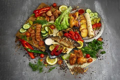 Assorted grilled meat on the grill with fried potatoes, cucumbers, cherry t.. Stock Photos