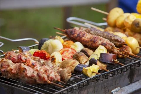 Assorted grilled meat with vegetables over the coals on a barbecue Stock Photos