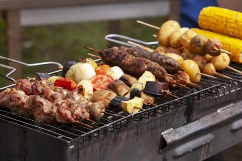 Assorted grilled meat with vegetables over the coals on a barbecue Stock Photos