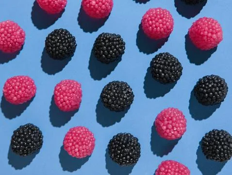 Assorted gummy candies shaped like berries top view on blue background Stock Photos