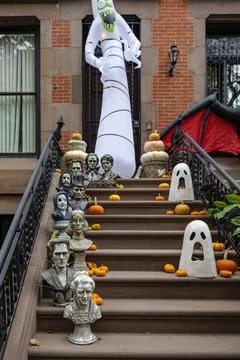 Assorted Halloween decorations guard the front steps of a house. Pumpkins on a Stock Photos