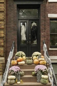 Assorted Halloween decorations guard the front steps of a house. Pumpkins on a Stock Photos