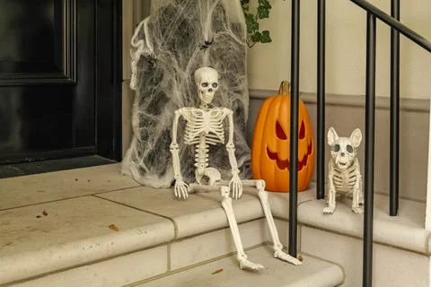 Assorted Halloween decorations guard the front steps of a house. Pumpkins on a Stock Photos