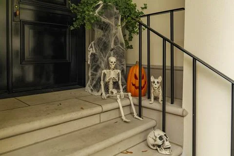 Assorted Halloween decorations guard the front steps of a house. Pumpkins on a Stock Photos