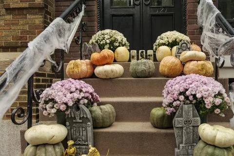 Assorted Halloween decorations guard the front steps of a house. Pumpkins on a Stock Photos