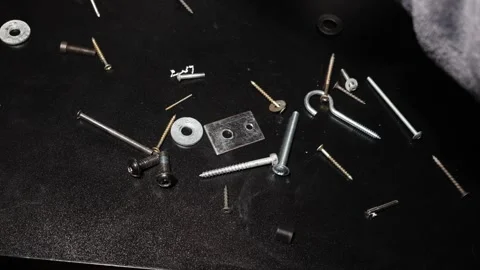 Assorted hardware and fasteners scattered on a dark textured surface Stock Footage 339180565