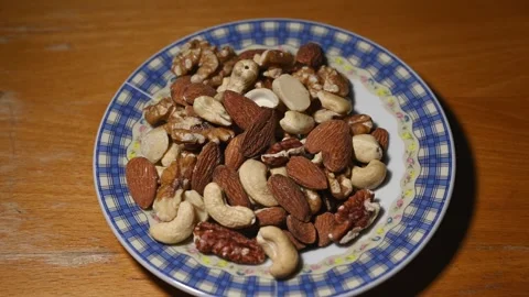 Assorted Healthy Nuts on Chinese Ceramic Plate with Changing Light Stock Footage 344954114