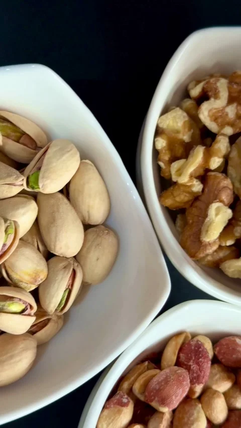Assorted healthy nuts served in three white ceramic bowls Stock Footage 331976010