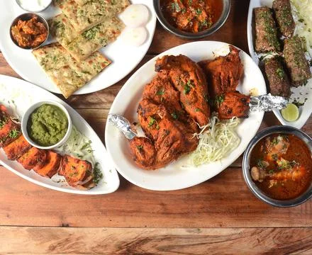 Assorted indian food on wooden background. Tandoori chicken,paneer tikka,kulc Stock Photos