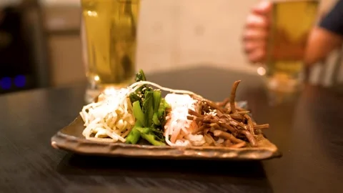 Assorted Japanese Namul Appetizer Plate with Beer in a Restaurant Stock Footage 336353713