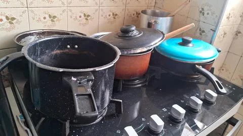 Assorted kitchen pots sitting on a black glass gas stove Stock Photos