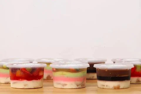 Assorted layered desserts in small clear cups on wooden surface Fotos Stock
